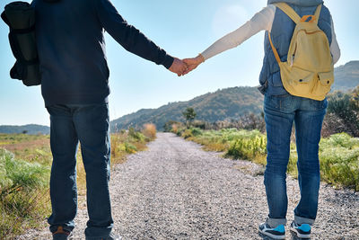 Loving couple holding hands while walking on rural road in autumn or spring nature.