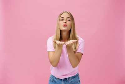 Portrait of a young woman against pink background