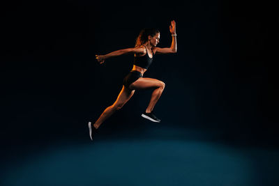 Full length of woman running against black background