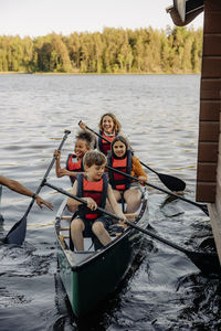 Happy kids kayaking with counselors on lake at summer camp