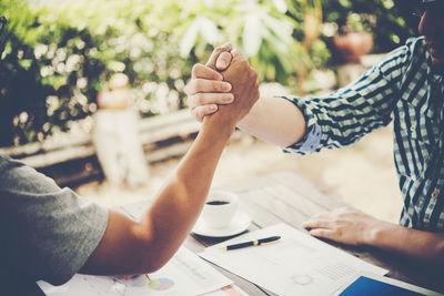 Close-up of colleagues arm wrestling at table