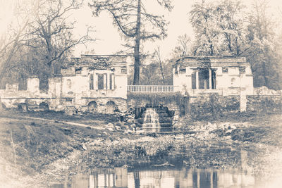 Digital composite image of building and trees by lake against sky