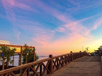 Railing by bridge against sky during sunset