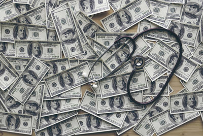 High angle view of stethoscope with paper currencies on table