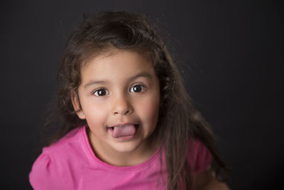 Close-up portrait of girl against black background