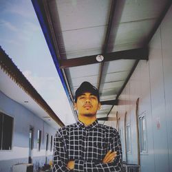 Portrait of young man standing against ceiling