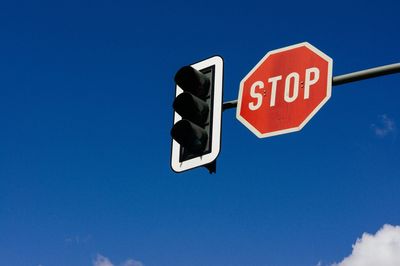 Low angle view of arrow sign against clear blue sky