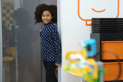 African american school girl entering modern class room door for science and constructing lesson