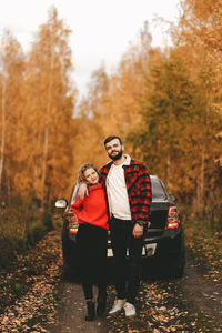 Portrait of young couple standing by trees during autumn