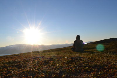 Rear view of man on field against sky during sunset