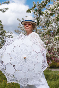 Portrait of woman wearing hat standing against trees