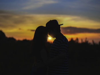 Silhouette couple embracing against orange sky during sunset