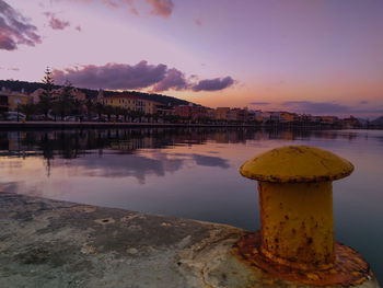 Scenic view of river by buildings against sky during sunset