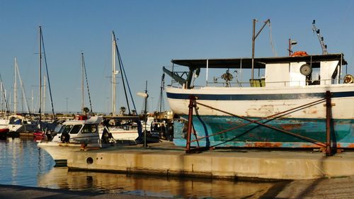 Boats moored at harbor against clear sky