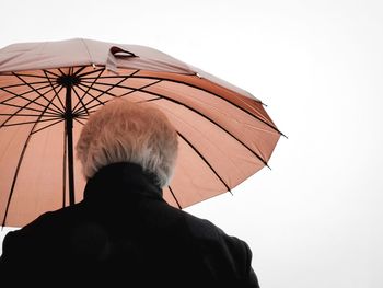 Rear view of woman standing with umbrella against sky