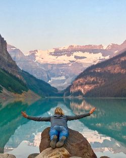 Rear view of man in lake against mountain range