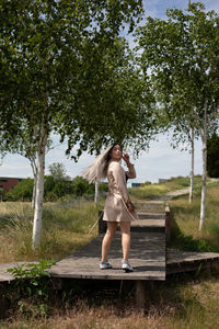 Full length of woman with arms raised against trees