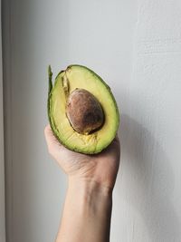 Midsection of person holding fruit against wall