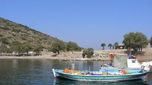 Boats moored in lake against clear blue sky