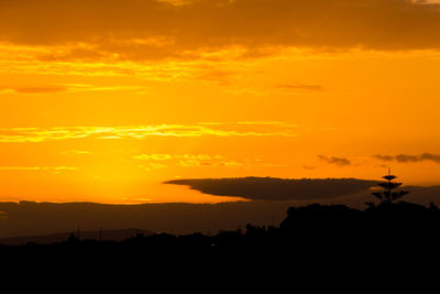 Silhouette landscape against dramatic sky during sunset