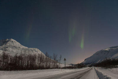 Scenic view of aurora borealis over snow covered road