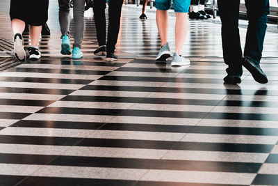 Low section of people walking on tiled floor