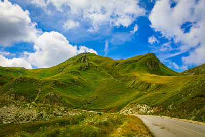 Road amidst green landscape against sky