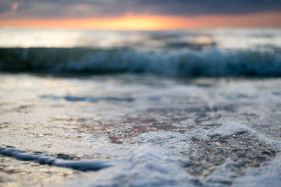 Surface level of beach against sky during sunset