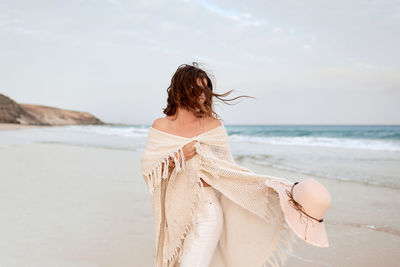 Woman standing at beach against sky