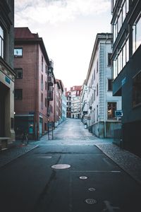 Road amidst buildings in city against sky