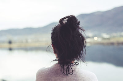 Rear view of woman looking at lake against sky