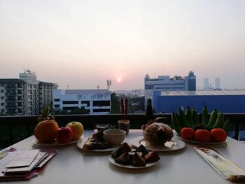 Food on table in city against sky during sunset