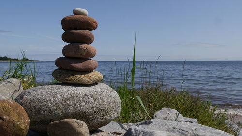 Stack of stones at shore against sky