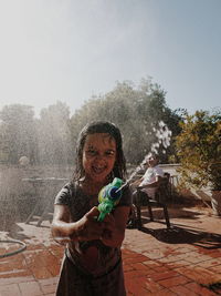 Portrait of smiling girl holding umbrella against clear sky