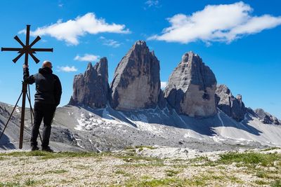 Rear view of man standing on rock against sky