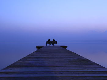 Pier over lake against sky during sunset