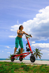 Low angle view of woman standing on vehicle against sky