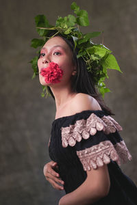 Portrait of young woman standing against plant