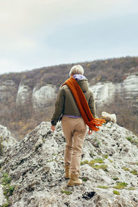 Rear view woman climbs a cliff in autumn in the crimea