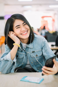 Portrait of a smiling young woman holding camera