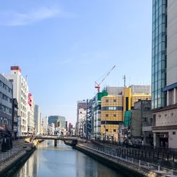 Bridge over river by buildings in city against sky