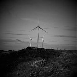 Windmills on field against sky