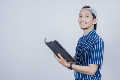 Mid adult man holding book against white background