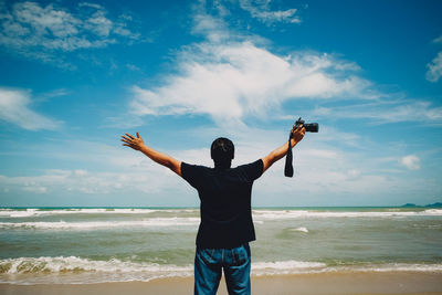 Rear view of man on beach against sky