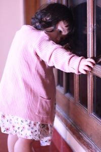 Midsection of woman holding pink while standing at home