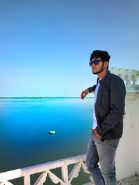 Fashionable young man looking away while standing by seascape