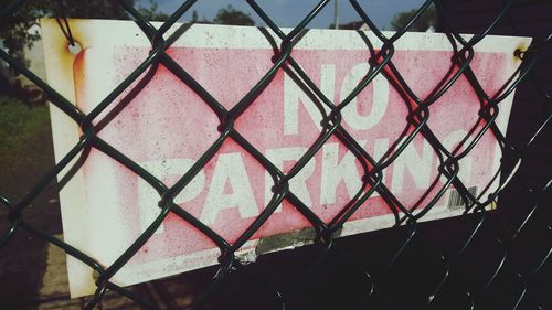 Close-up of no parking sign behind chainlink fence