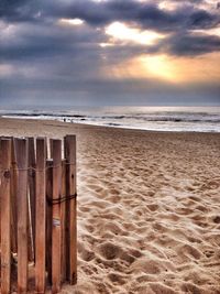 View of calm beach against cloudy sky