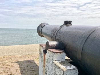 Close-up of coin-operated binoculars on retaining wall by sea against sky