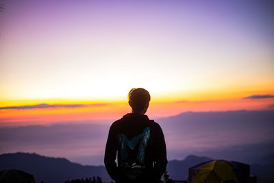 Rear view of man standing against sky during sunset